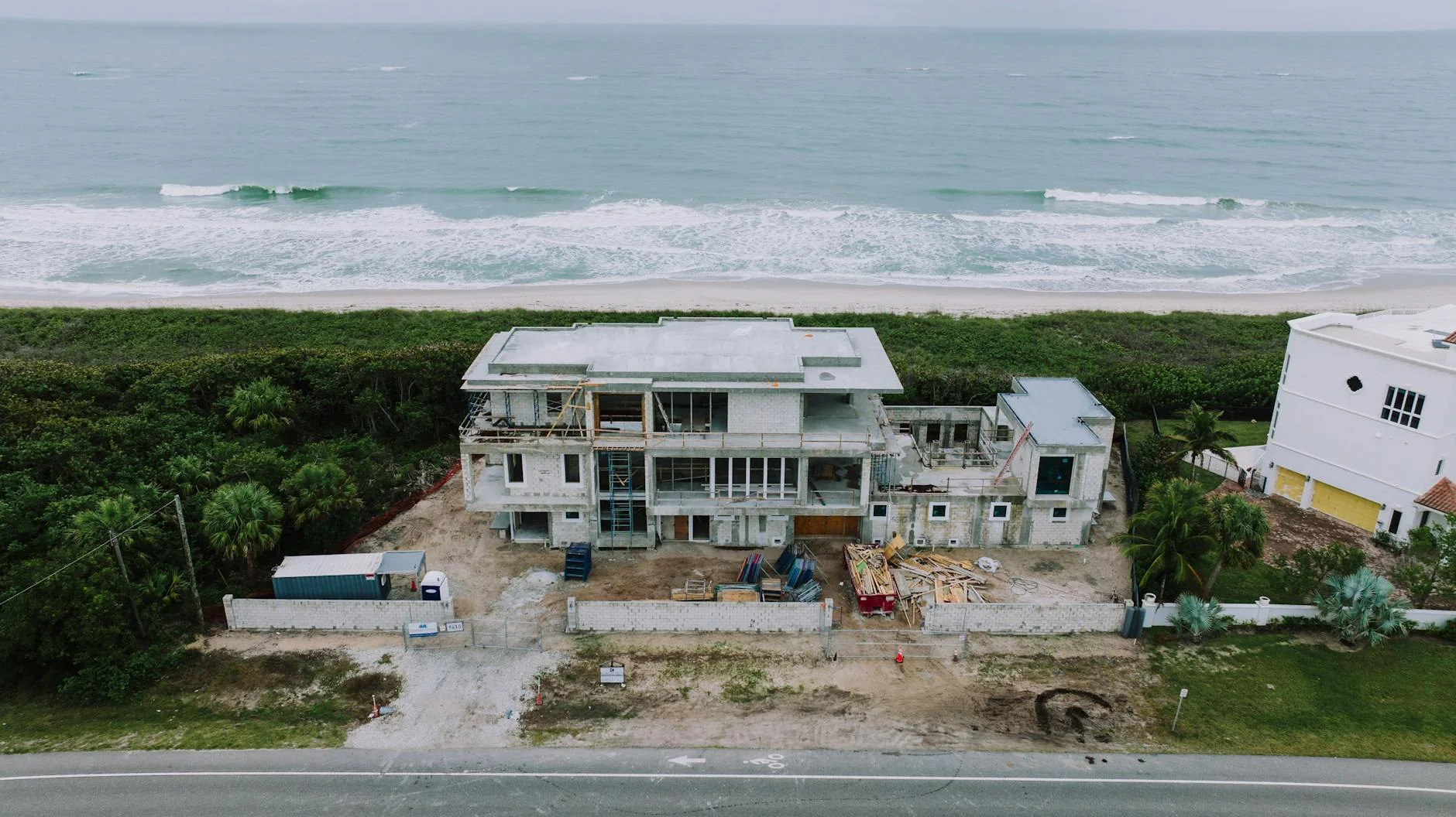 Florida construction site with palm trees in the background and a contractor reviewing a clipboard