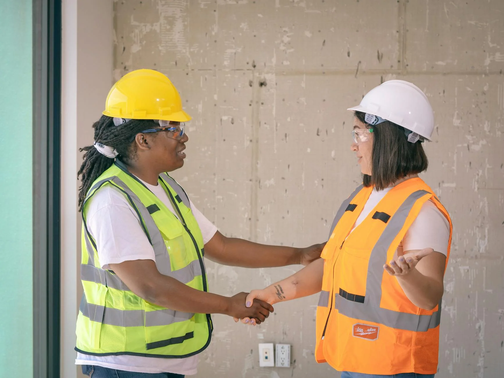 Subcontractor signing a paper document on a job site clipboard with a hard hat resting on the table